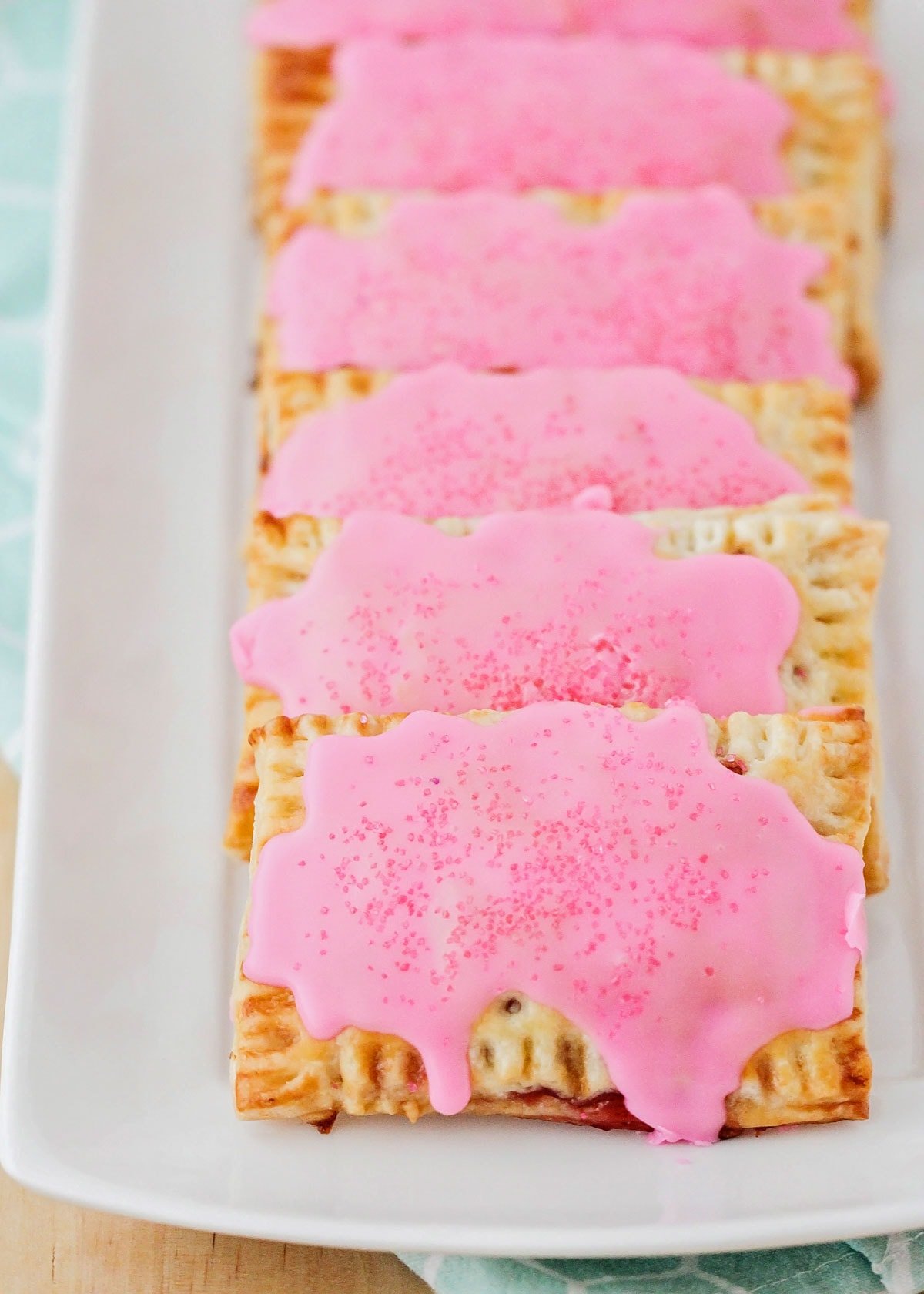 Homemade pop tarts with strawberry frosting on top.