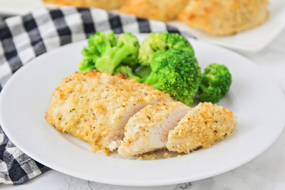 Sliced baked ranch chicken on a white plate with broccoli.