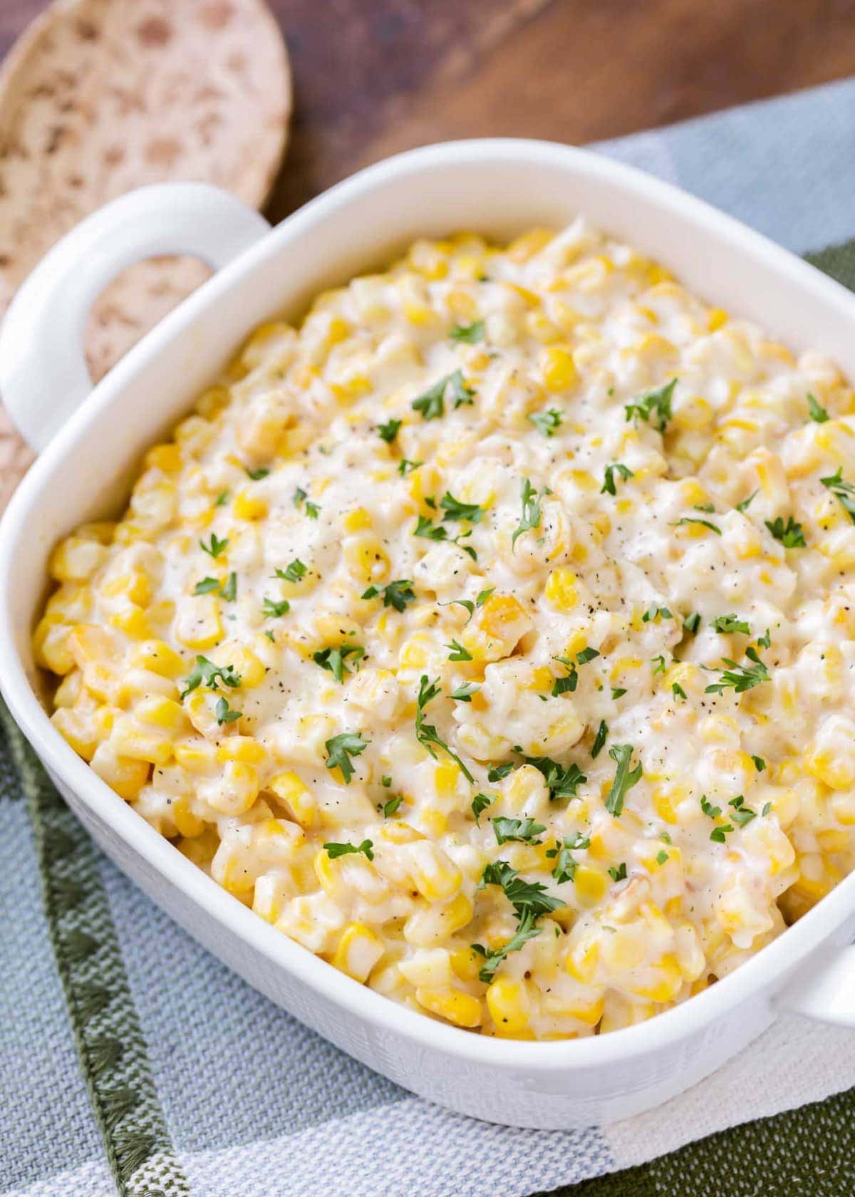 Creamed corn recipe served in a baking dish, topped with fresh herbs.