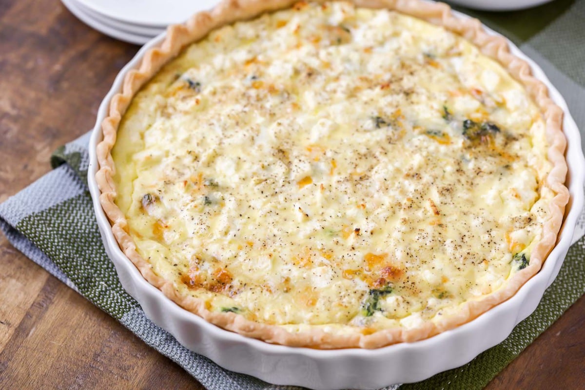 baked spinach quiche in a white tart pan