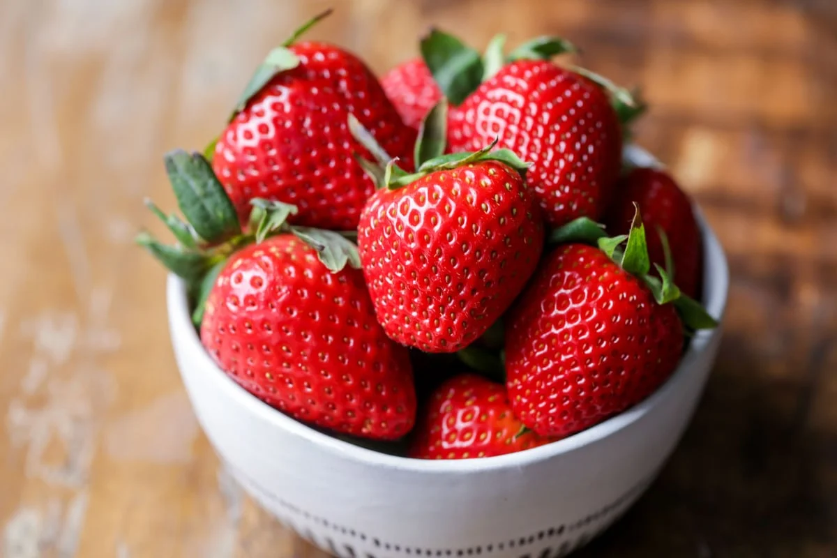 Fresh strawberries in a white bowl image.