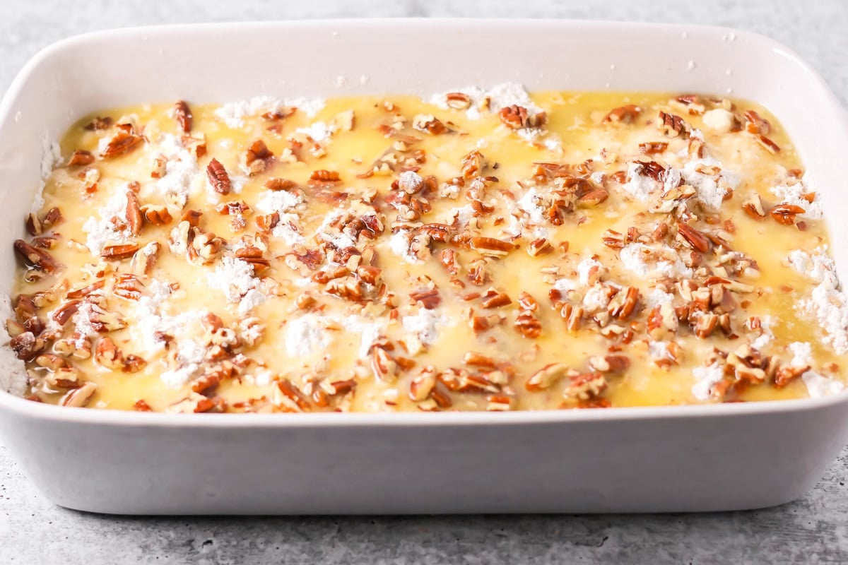 Butter and pecans poured over cake mix batter on pumpkin cake.