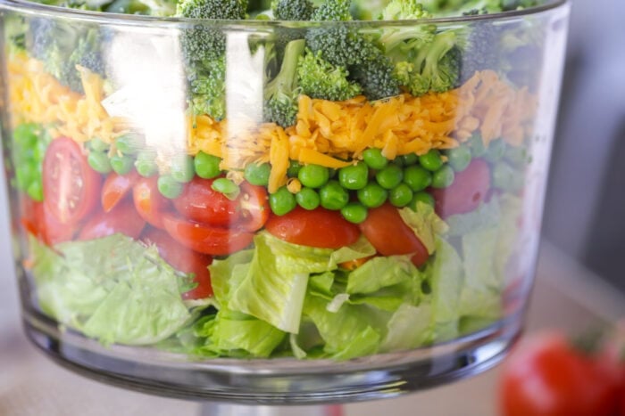 Deliciously customizable 7 Layer Salad is filled with just the right amount of goodness. It's perfect to make ahead! 7 Layer salad in a glass trifle dish