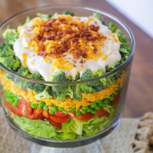 7 layer salad in a glass trifle bowl.