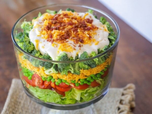 7 layer salad in a glass trifle bowl.