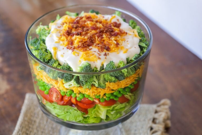 7 layer salad in a glass trifle bowl.