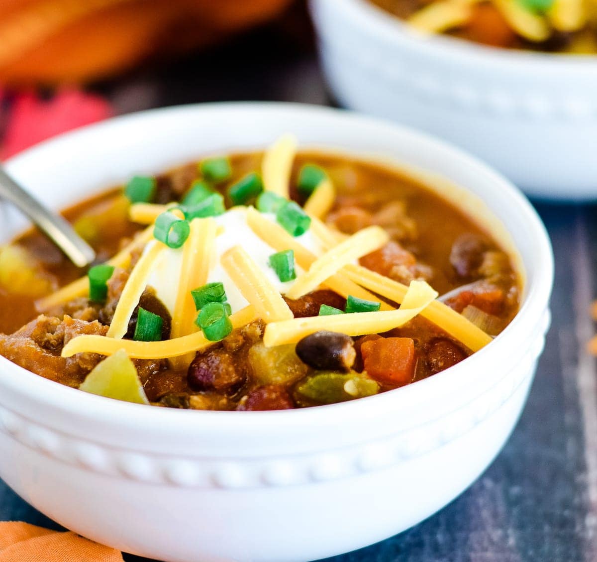 Pumpkin recipes - White bowl of pumpkin chili topped with cheese and sour cream.