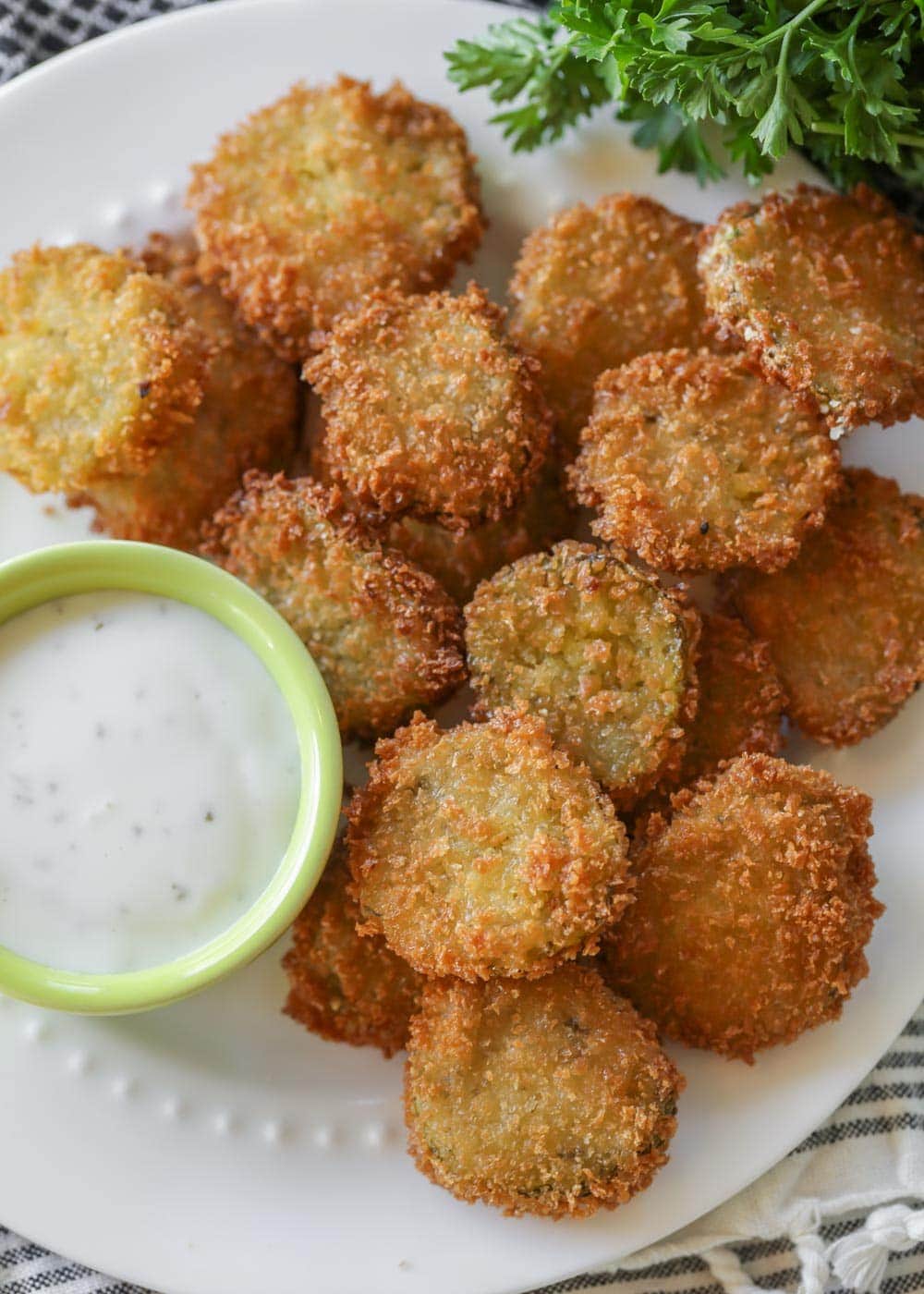 Close up of deep fried pickles on a plate with ranch dressing.