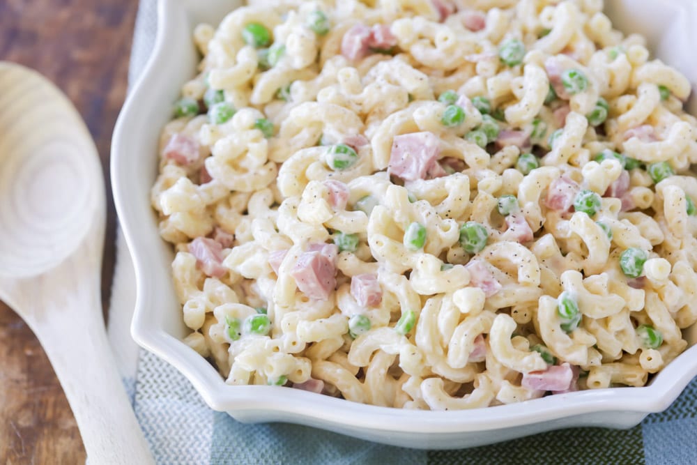 Macaroni salad with peas and ham in a white serving dish