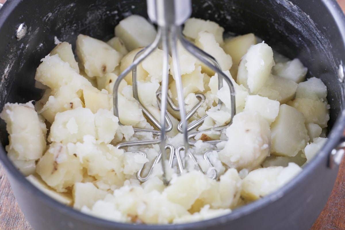 Smashing cooked potatoes for best mashed potatoes.