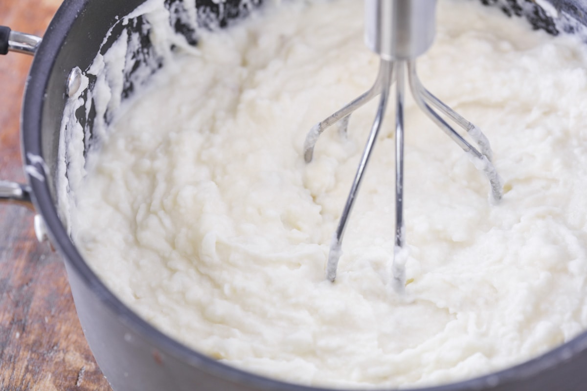 Whipping best mashed potatoes in a pot.
