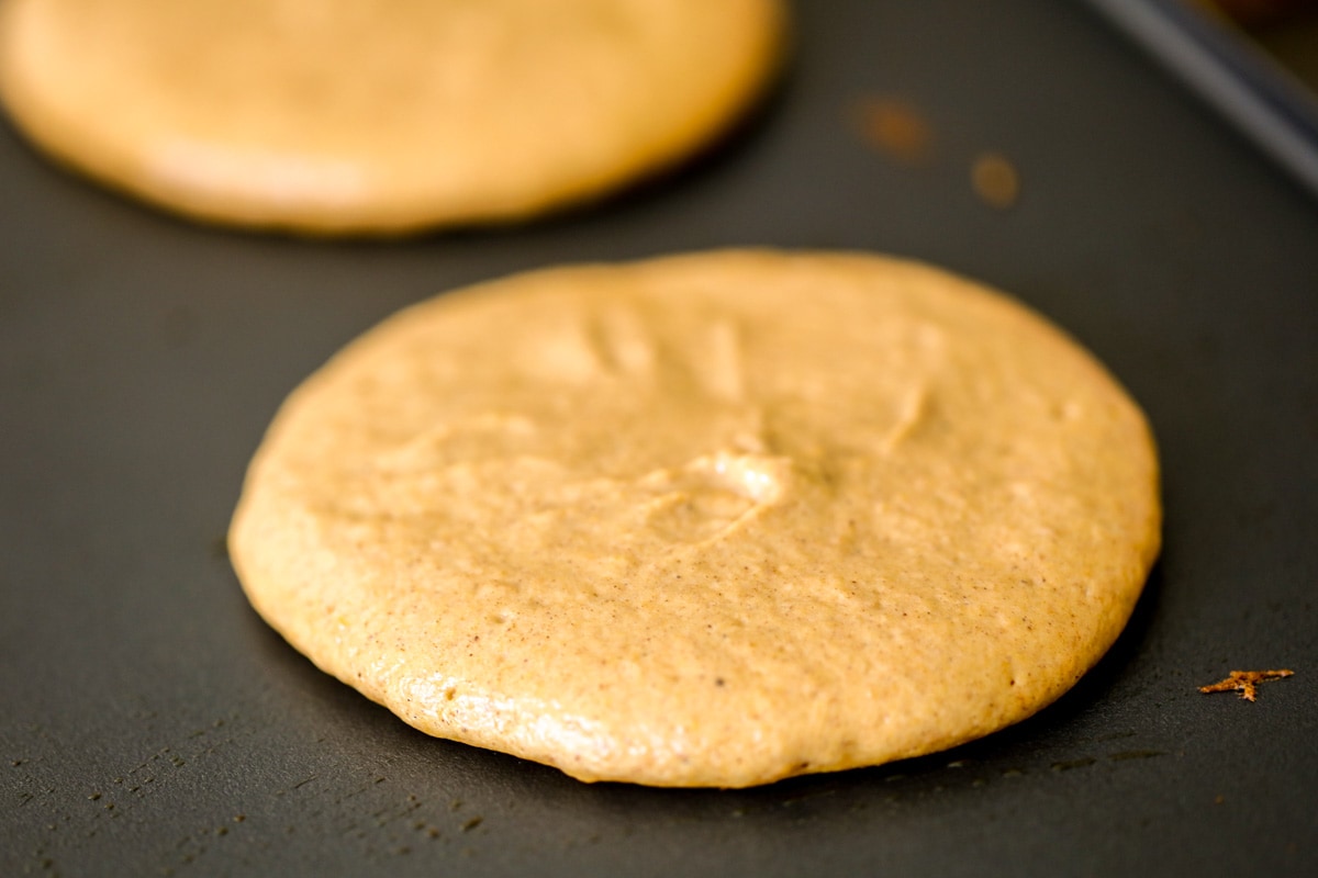 Pumpkin pancake batter cooking on griddle.