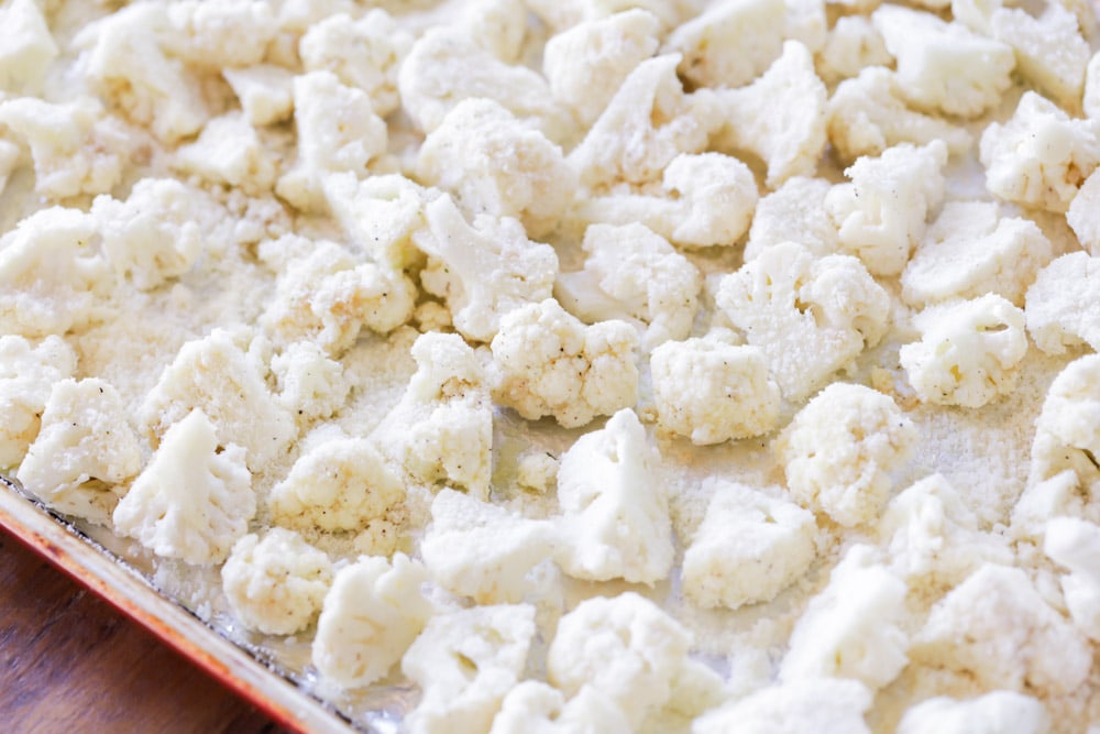 cauliflower covered in parmesan on a baking sheet