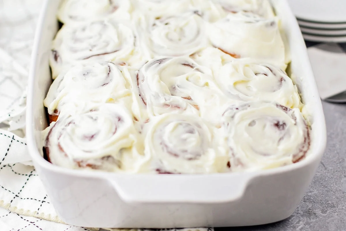 Cinnamon rolls freshly iced with frosting.