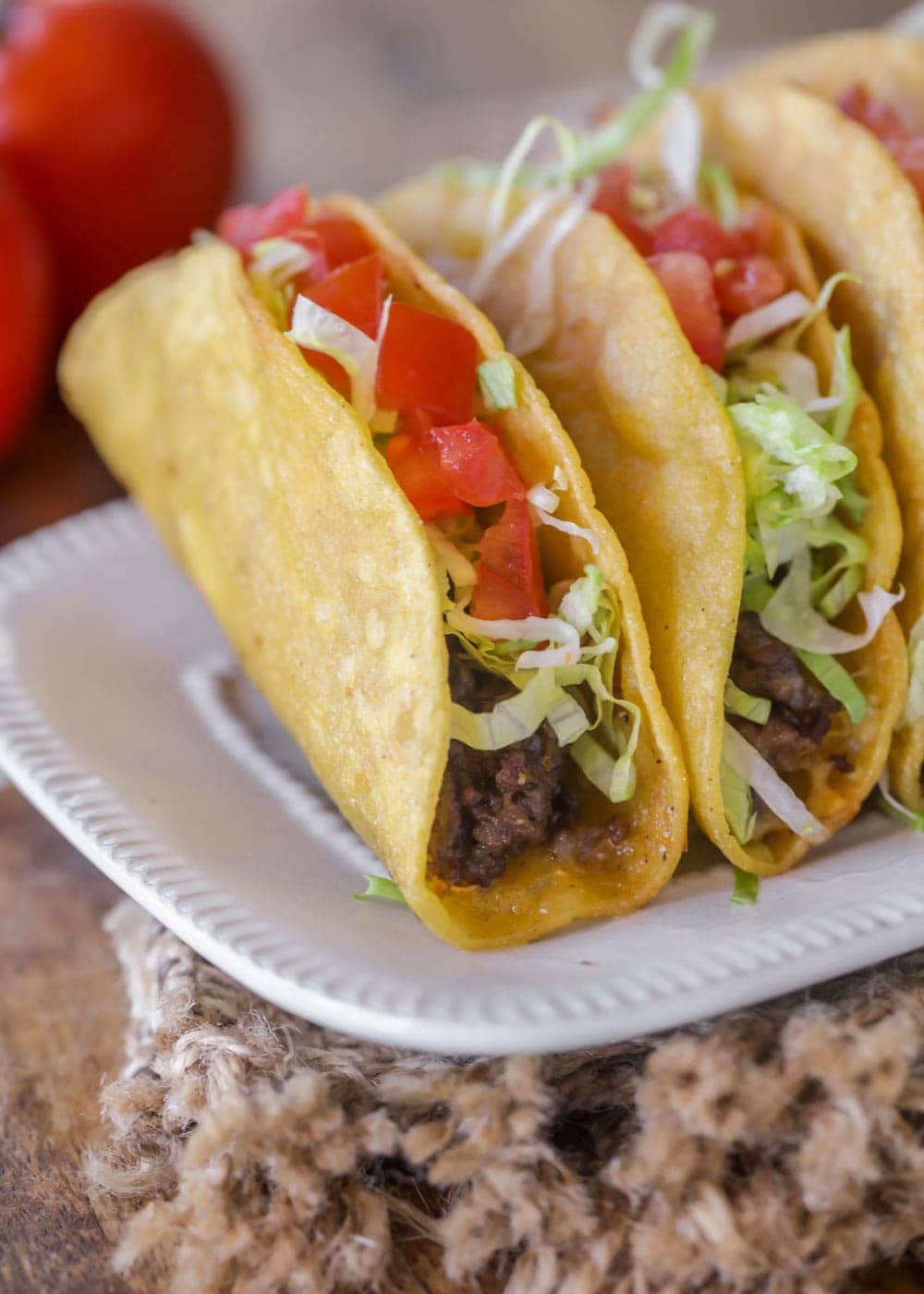 Ground beef tacos recipe topped with lettuce and tomatoes.