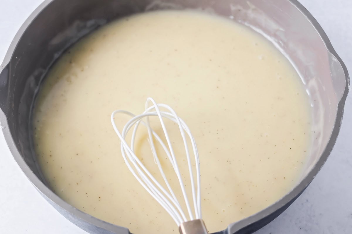 Whisking turkey gravy without drippings in a pan.