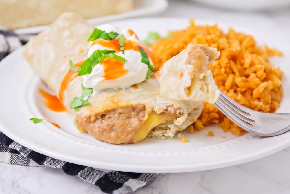 Mexican Christmas food - a forkful of a bean burrito served with Spanish rice.