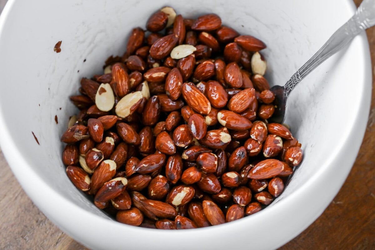 Mixing almonds in a white bowl.