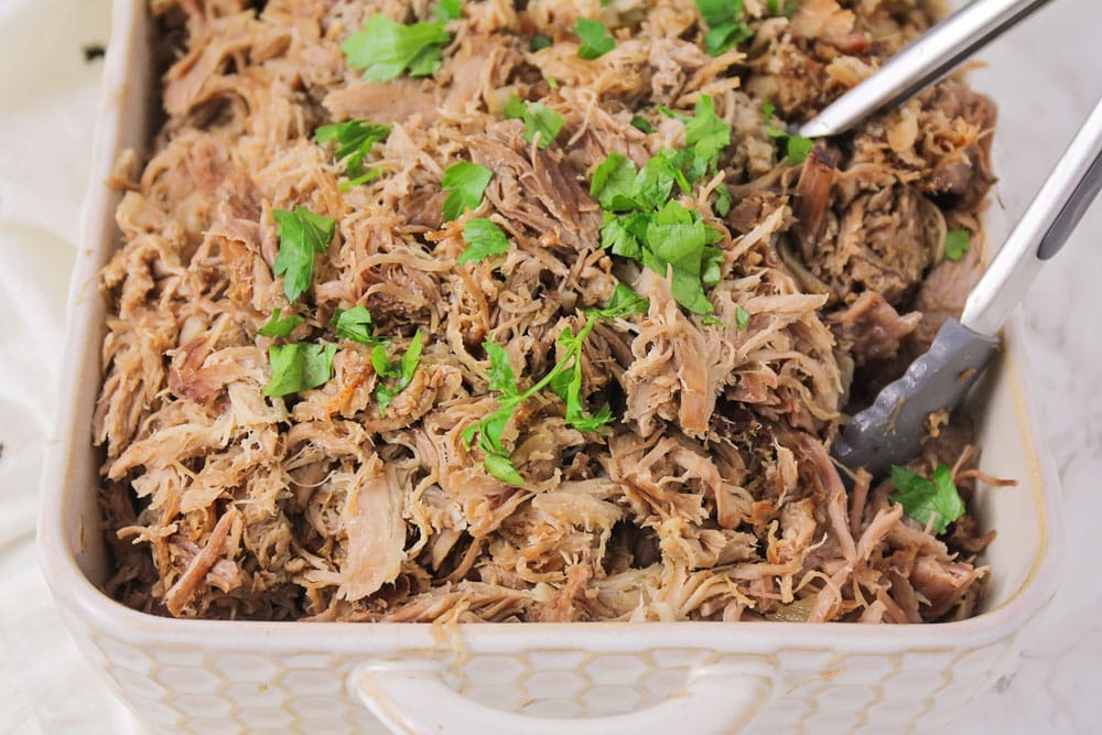 Carnitas recipe topped with cilantro in baking dish.