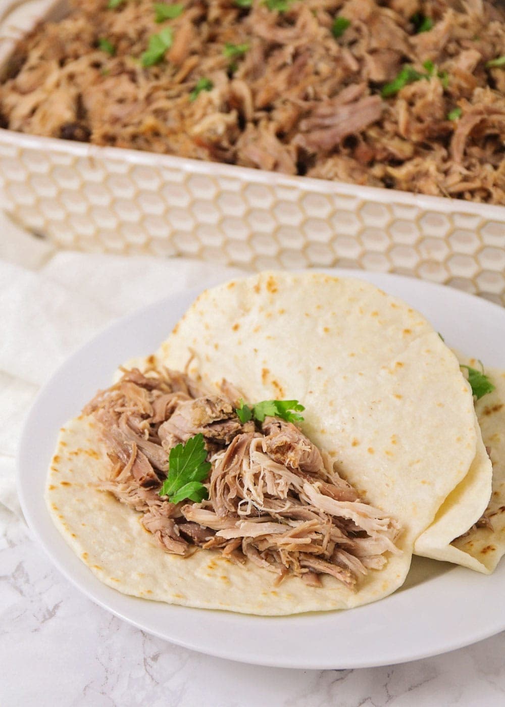 Close up of two pork carnitas tacos topped with cilantro.