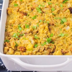 A baking dish of cooked cornbread stuffing topped with fresh herbs.
