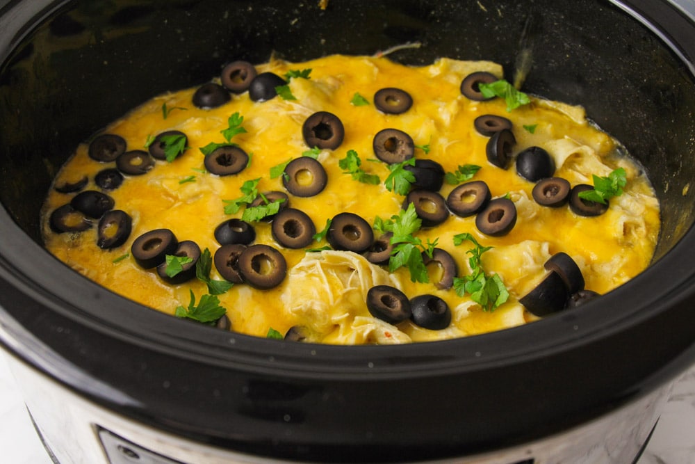 Slow cooker chicken enchiladas topped with black olives.