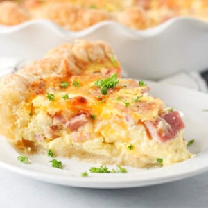 Ham and cheese quiche slice on white plate.
