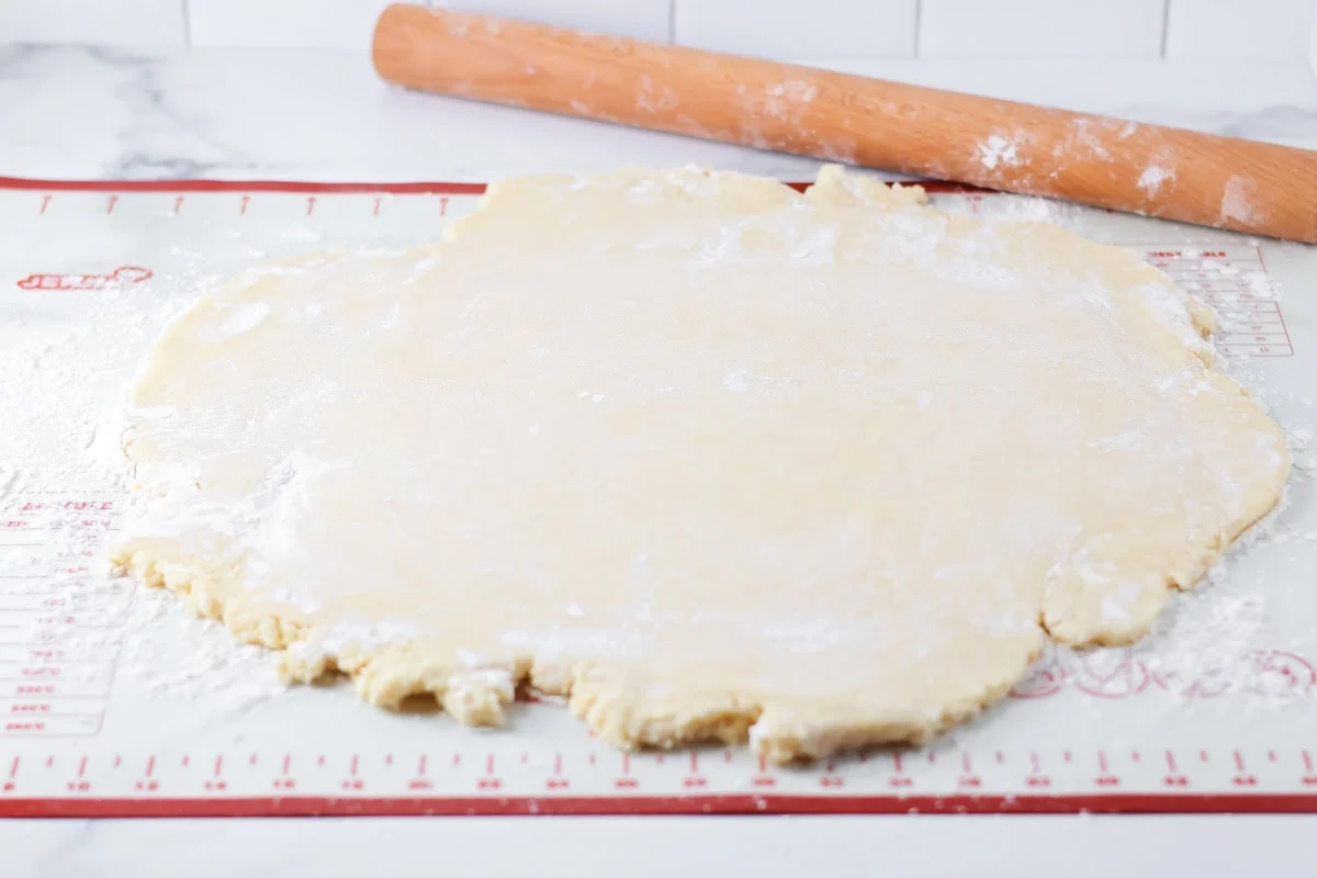 Rolled out sugar cookie dough on a pastry mat.