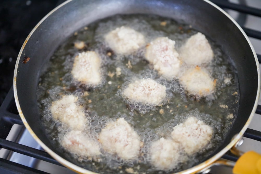 Frying up homemade popcorn chicken in a pan of oil.