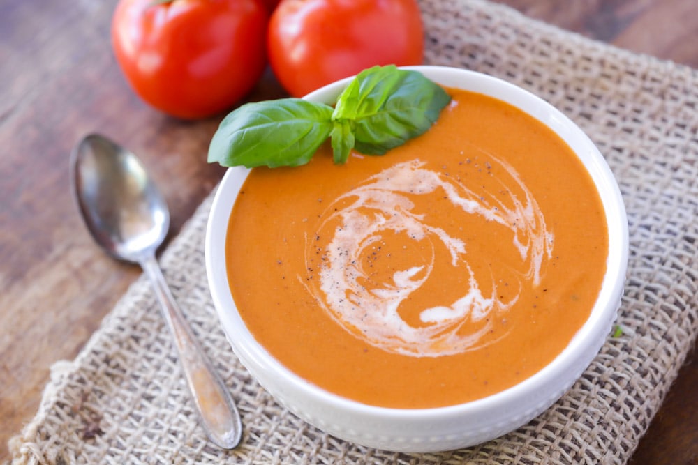 Best Easy Soup Recipes - Tomato bisque in a white bowl topped with fresh basil.
