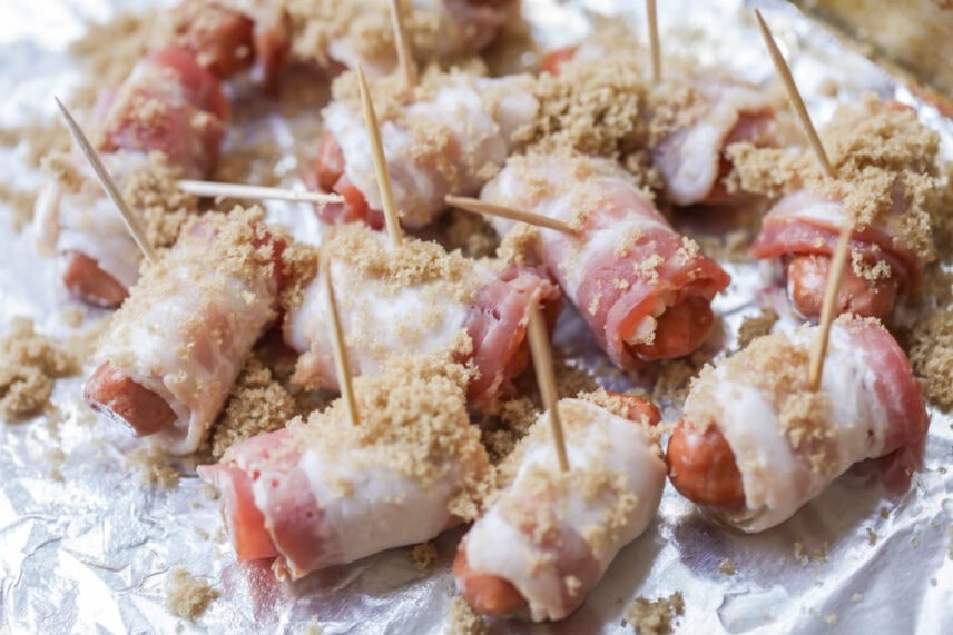Just 3 ingredients to make candied Bacon Wrapped Smokies. They are the ultimate appetizer and always the first to disappear! Brown sugar sprinkled on bacon wrapped smokies.