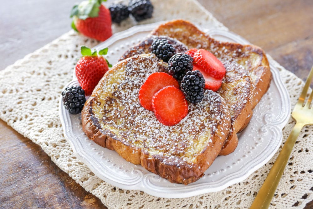 Brioche french toast topped with powdered sugar and berries