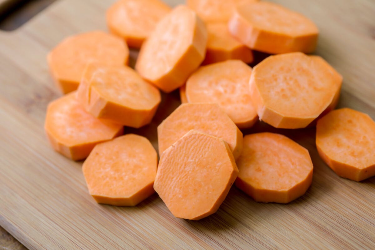 Sweet potato cut into discs on cutting board.