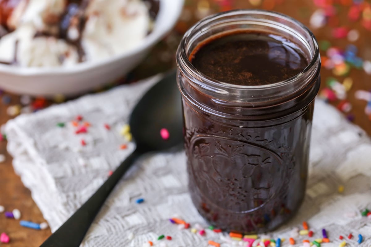 Chocolate syrup in a glass jar with a spoon