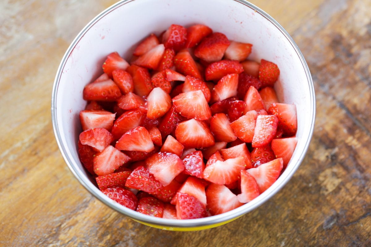 Cut up strawberries in a white bowl.
