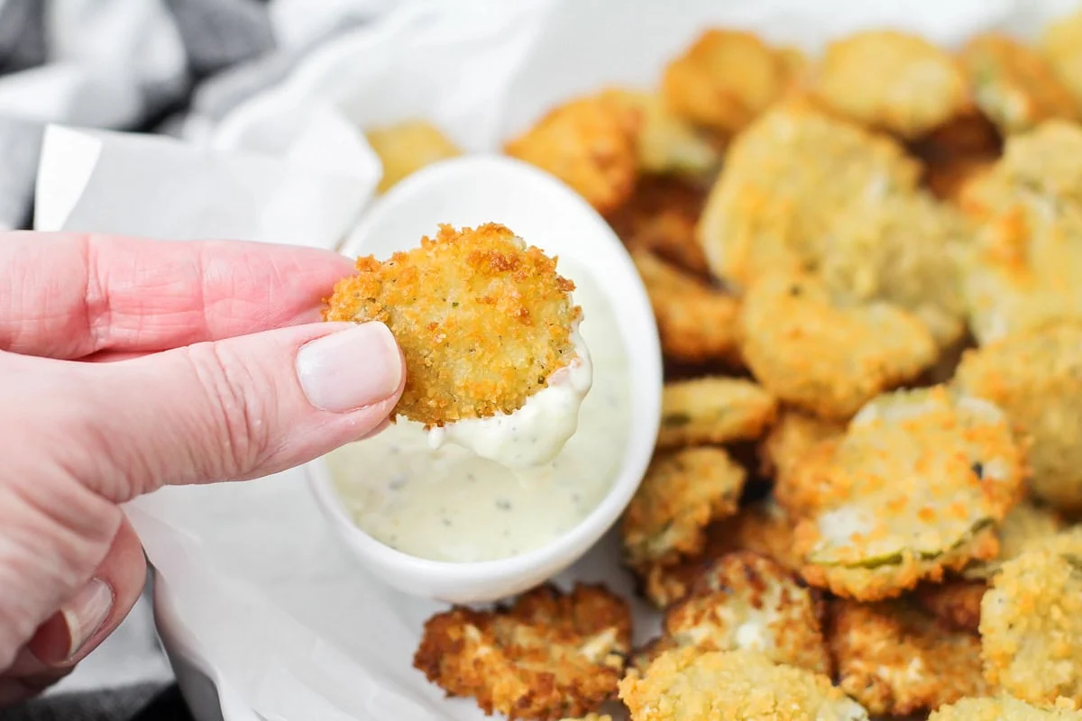 Fried pickles being dipped in ranch.