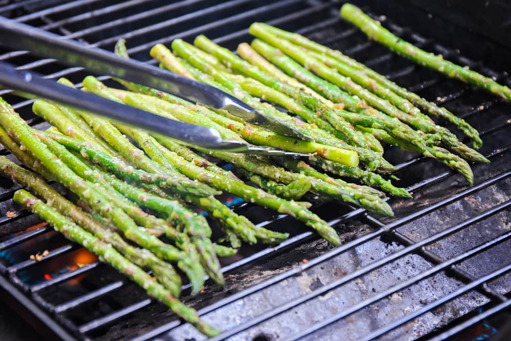 Grilling asparagus on the grill with tongs