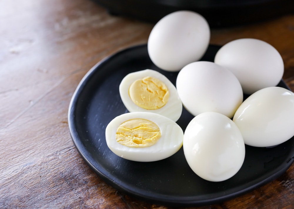 Breakfast Egg Recipes - hardboiled eggs with one egg cut in half on a black plate. 