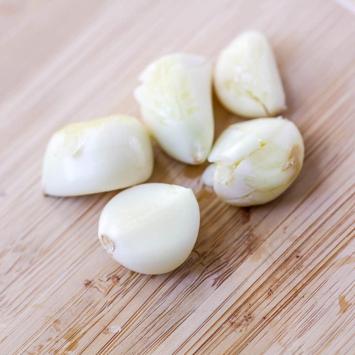 Five peeled garlic cloves ready to be minced.