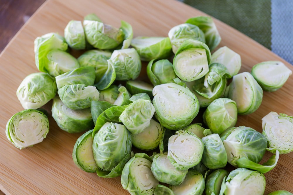 Easter Side Dishes - fresh Brussel sprouts cut in half on a wooden cutting board. 