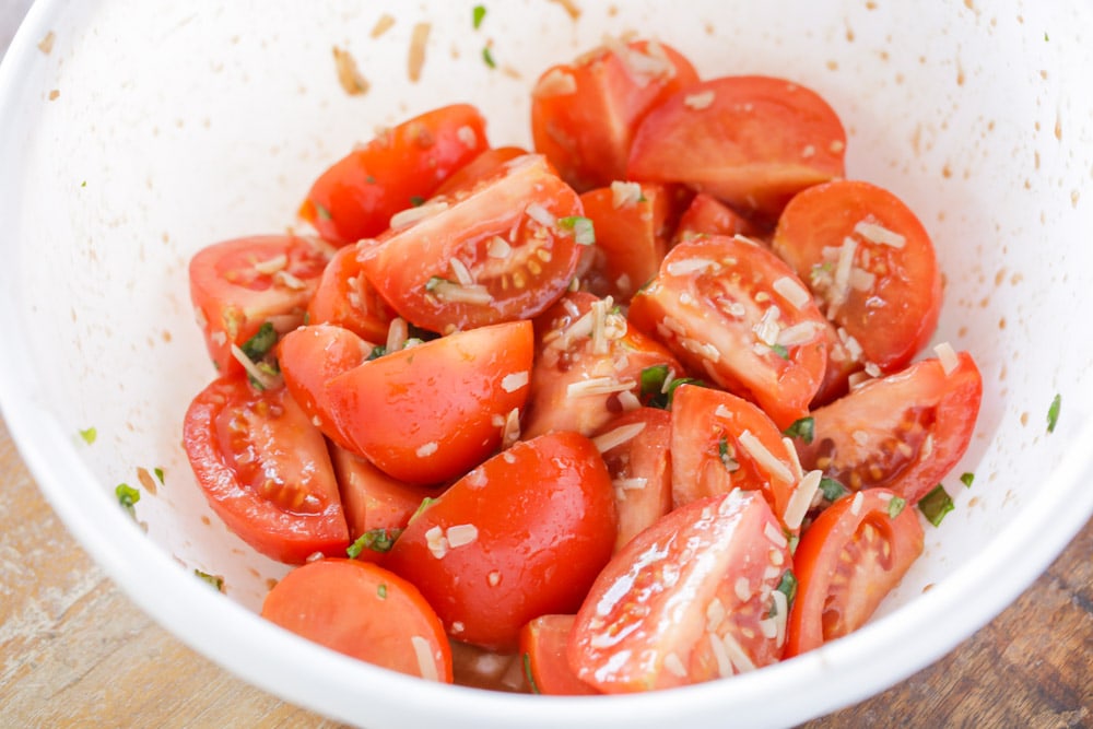 Fresh tomatoes covered in olive oil, basil, and parmesan