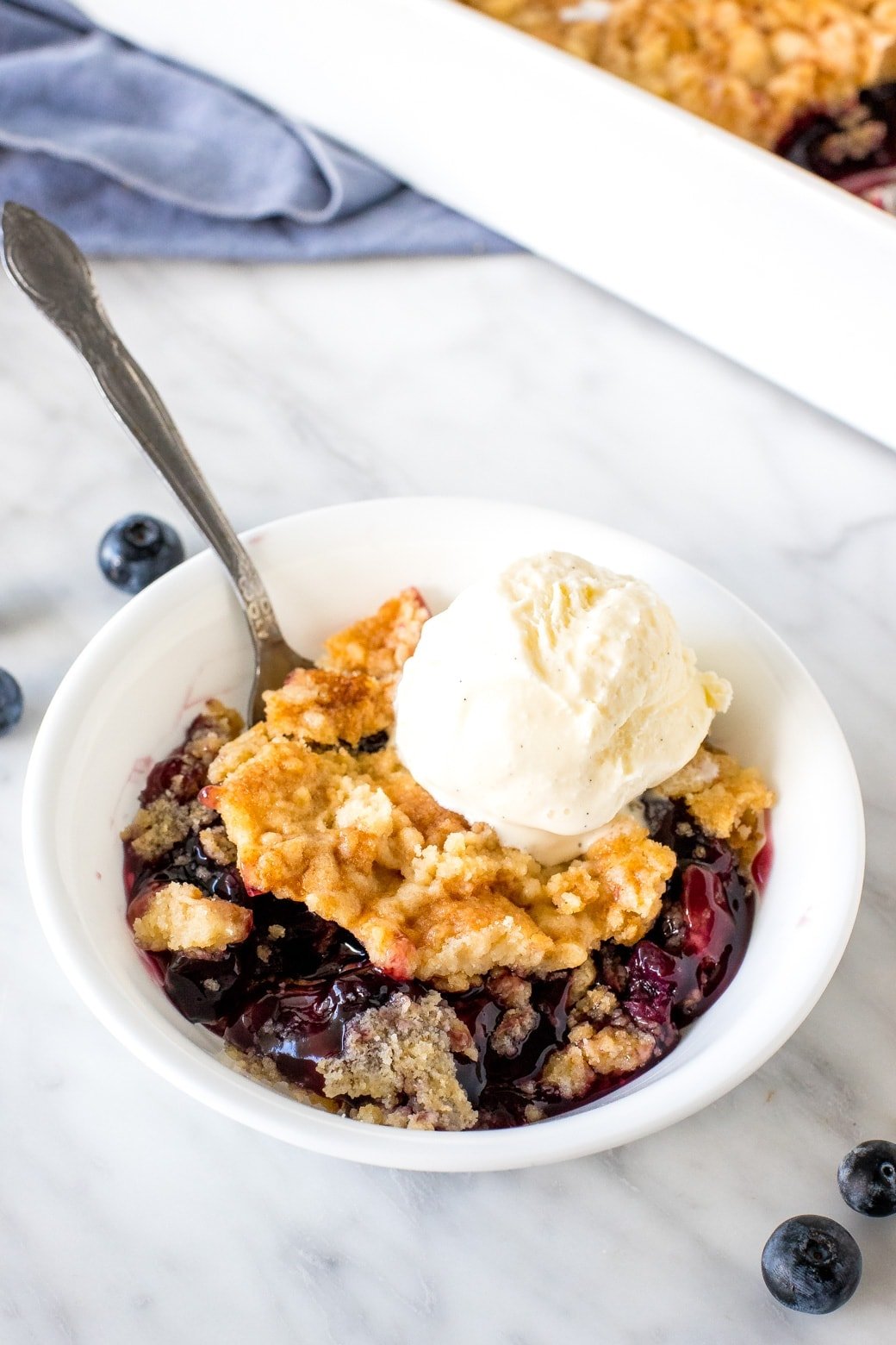 Bowl of blueberry dump cake with a scoop of vanilla ice cream. 