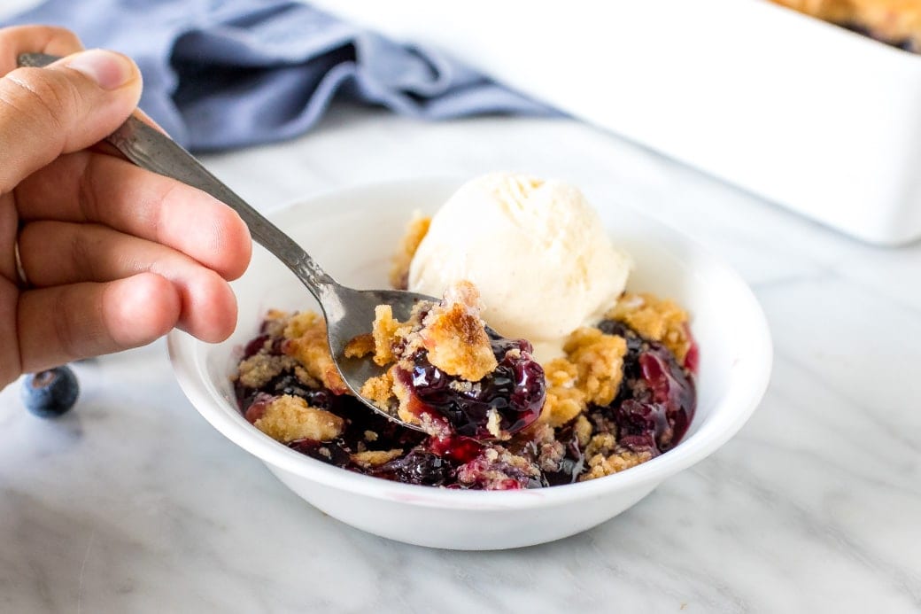 Easy Cake Recipes - Close up of a spoonfull of blueberry dump cake.