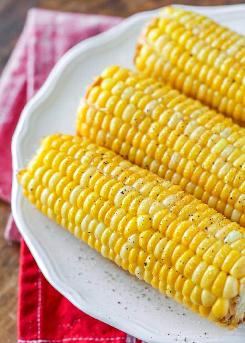 Boiled corn on the cob sitting on a white plate