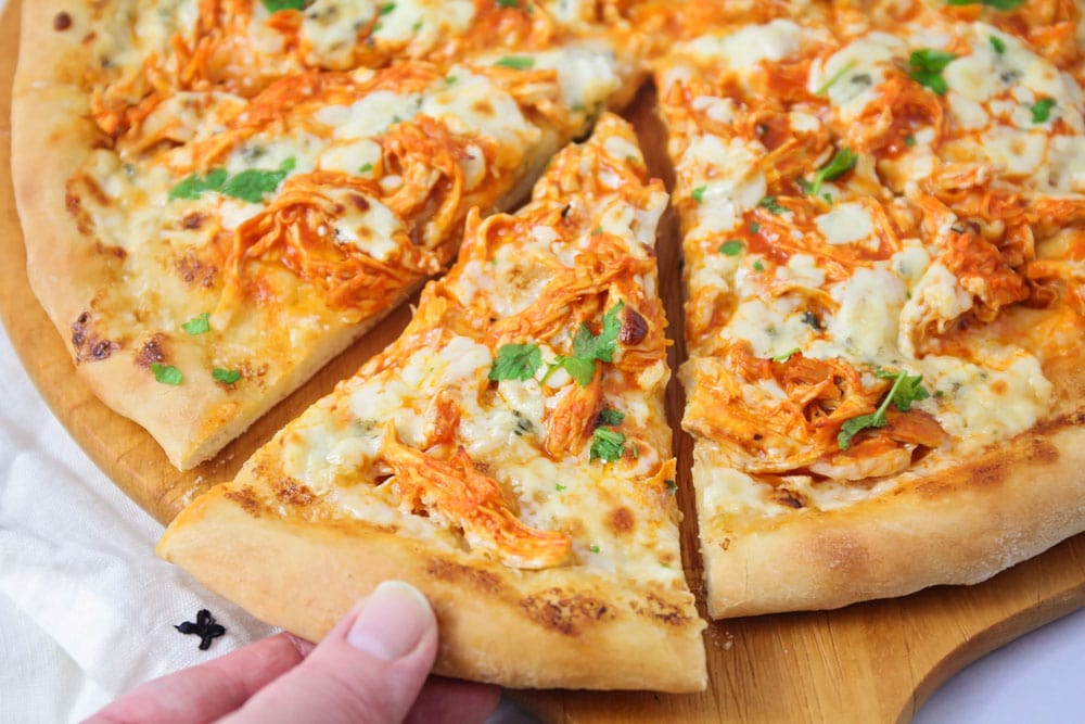 Buffalo chicken pizza sliced and topped with cilantro.