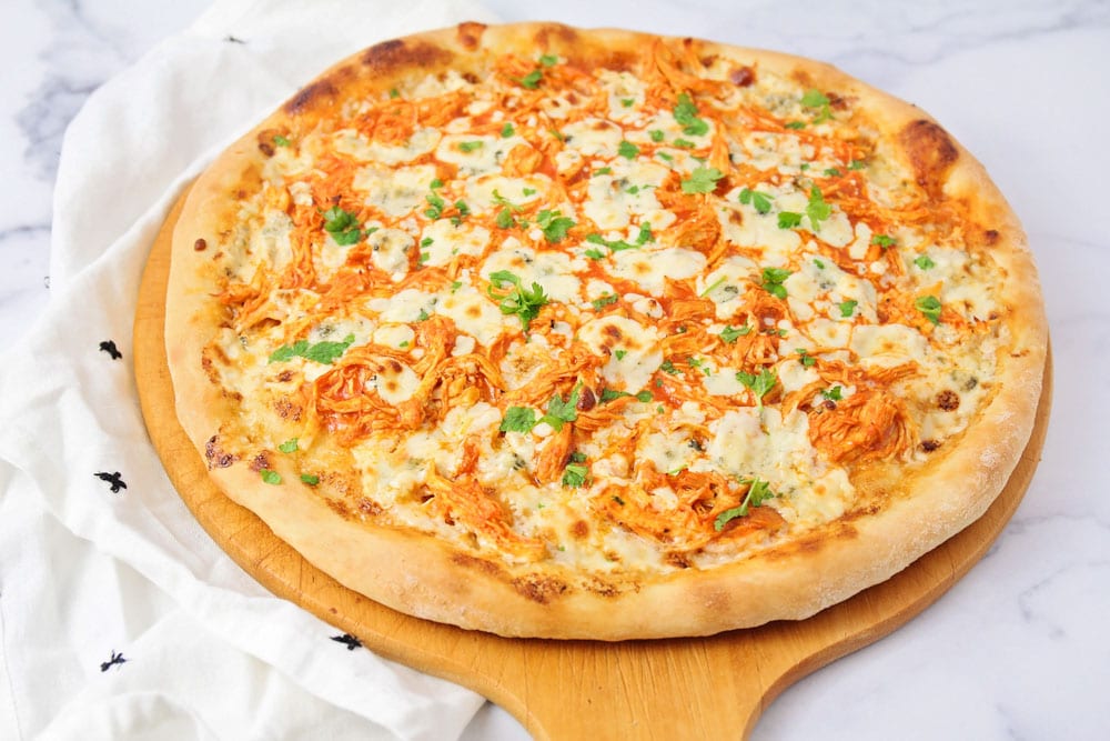 Chicken Dinner Ideas - Buffalo chicken pizza fresh from the oven on a wooden pizza paddle.