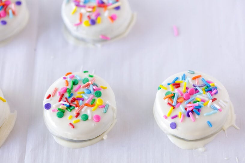 White chocolate covered oreos topped with sprinkles.