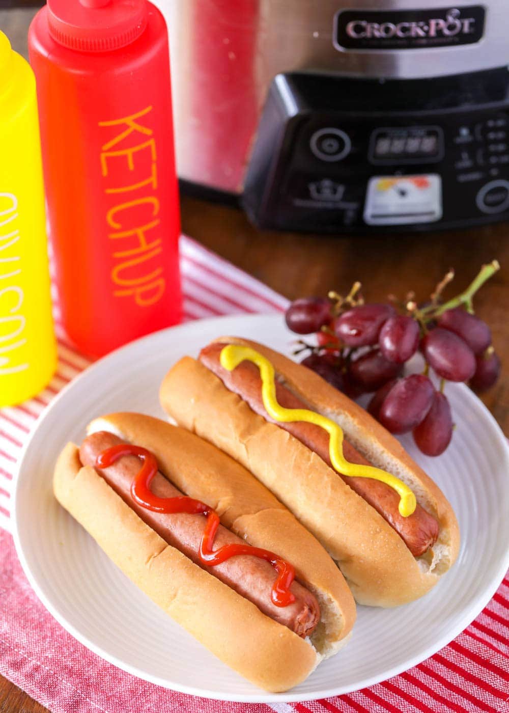 Hot dogs in crock pot served on buns with ketchup and mustard.