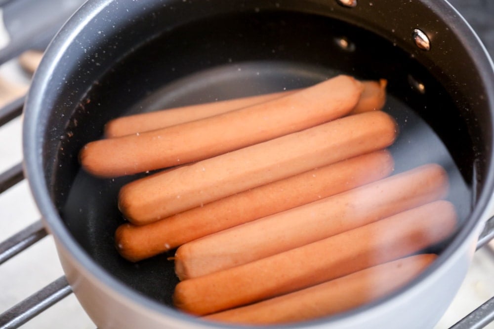 Boiling hot dogs in a saucepan on the stove.