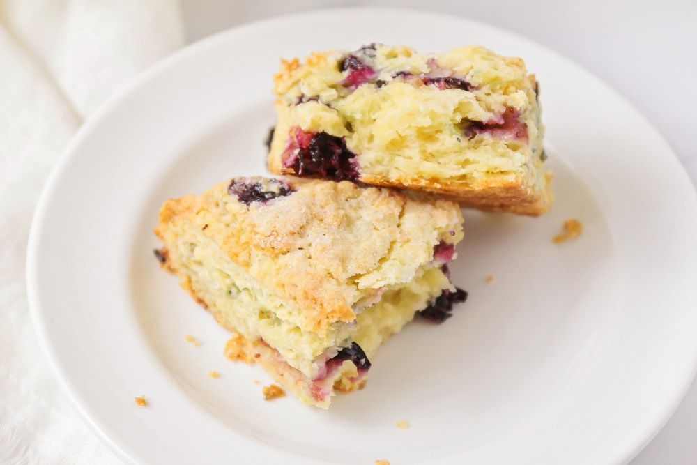 Two blueberry scones stacked on a white plate.